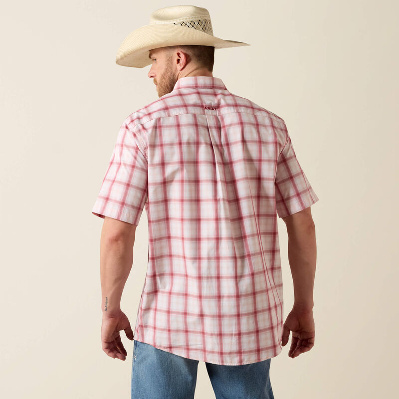 Man wearing a red and white plaid shirt and beige cowboy hat on a beige background