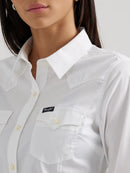 Close-up of a woman wearing a long sleeve wrangler shirt in a white with a spread collar, button front placket, and button flap pockets.