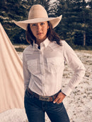 A woman wearing a long sleeve white Wrangler shirt with a spread collar, front yokes, button flap front pocket and button down front pockets.