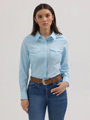 Full view of a woman wearing a long sleeve cool blue Wrangler shirt with a spread collar, front yokes, button flap front pocket and button down front pockets.