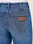 Close-up of Women's Bailey Retro bootcut jeans in Josephine blue wash with a Wrangler logo on back right pocket .