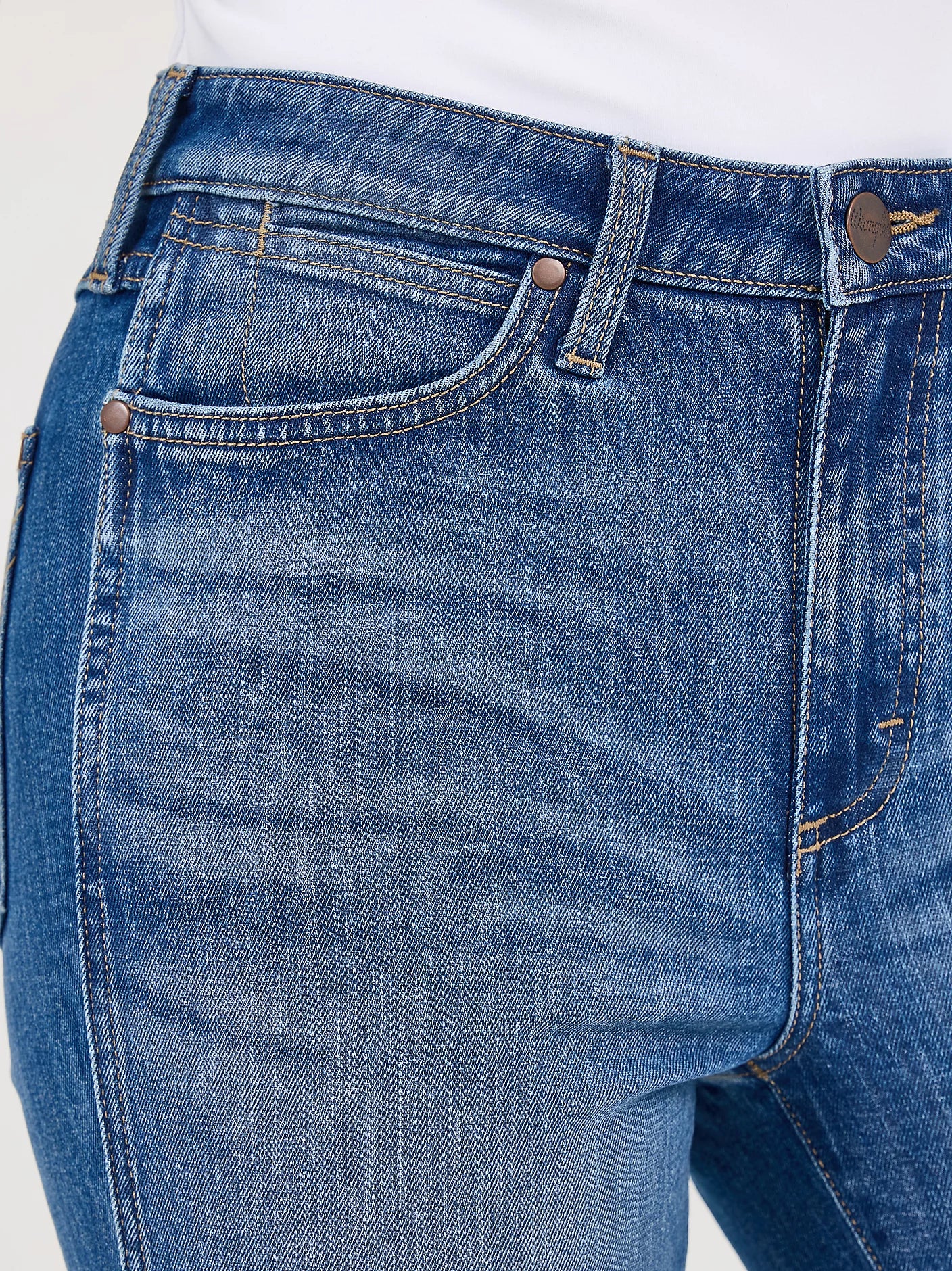 Close-up of Women's Bailey Retro bootcut jeans in Josephine blue wash with a coin and scoop right pocket . Also shows rivets on pocket tops and detail of front button and zipper closure.