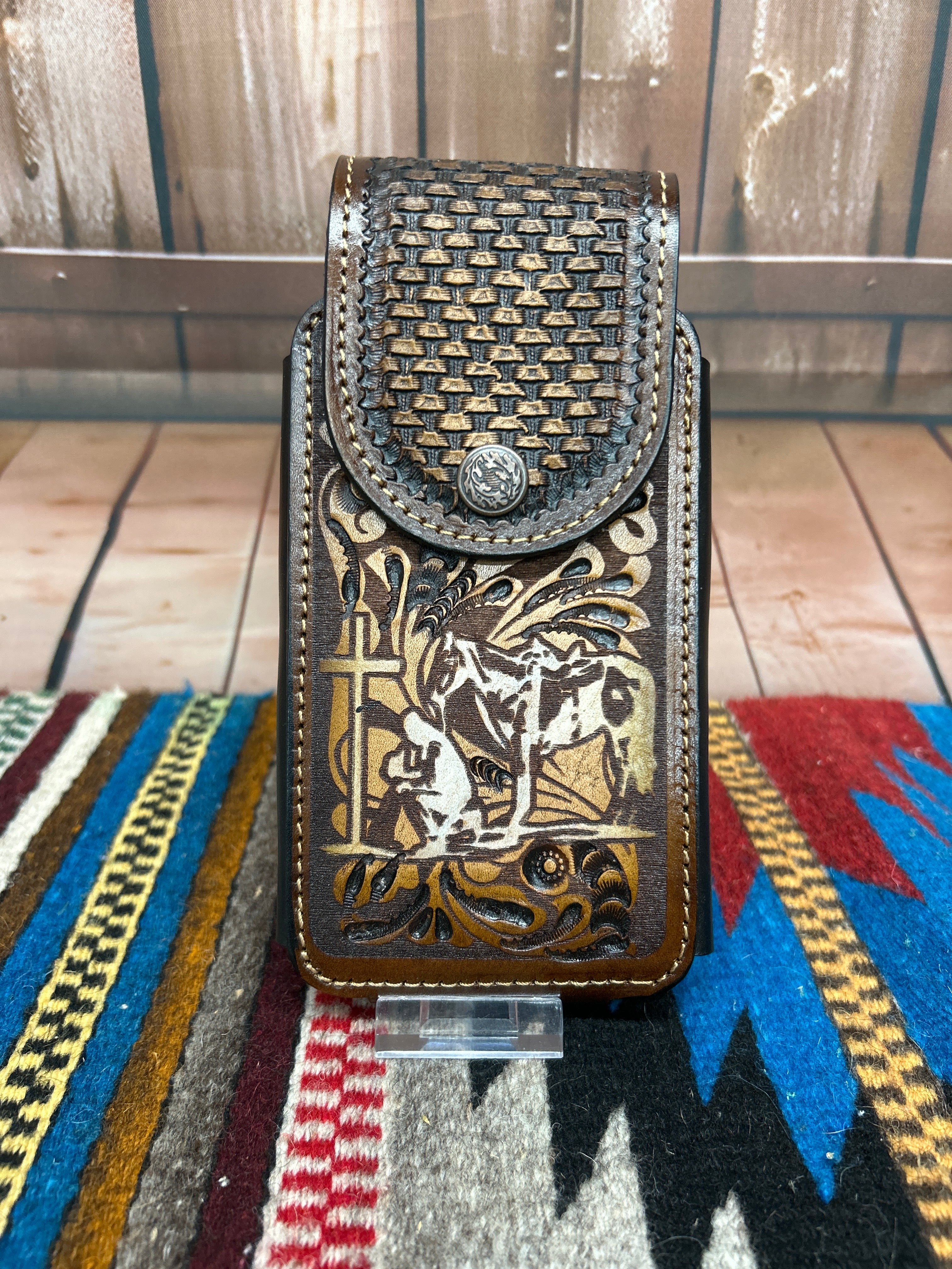 This leather phone case has a Praying Cowboy design on the front. It has a snap closure and a leather belt loop for attachment. This case measures 7 1/4 inches tall, and 3 5/8 inches wide empty. Front View