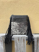 This black leather and cowhide crossbody bag has fringe details along the sides. 