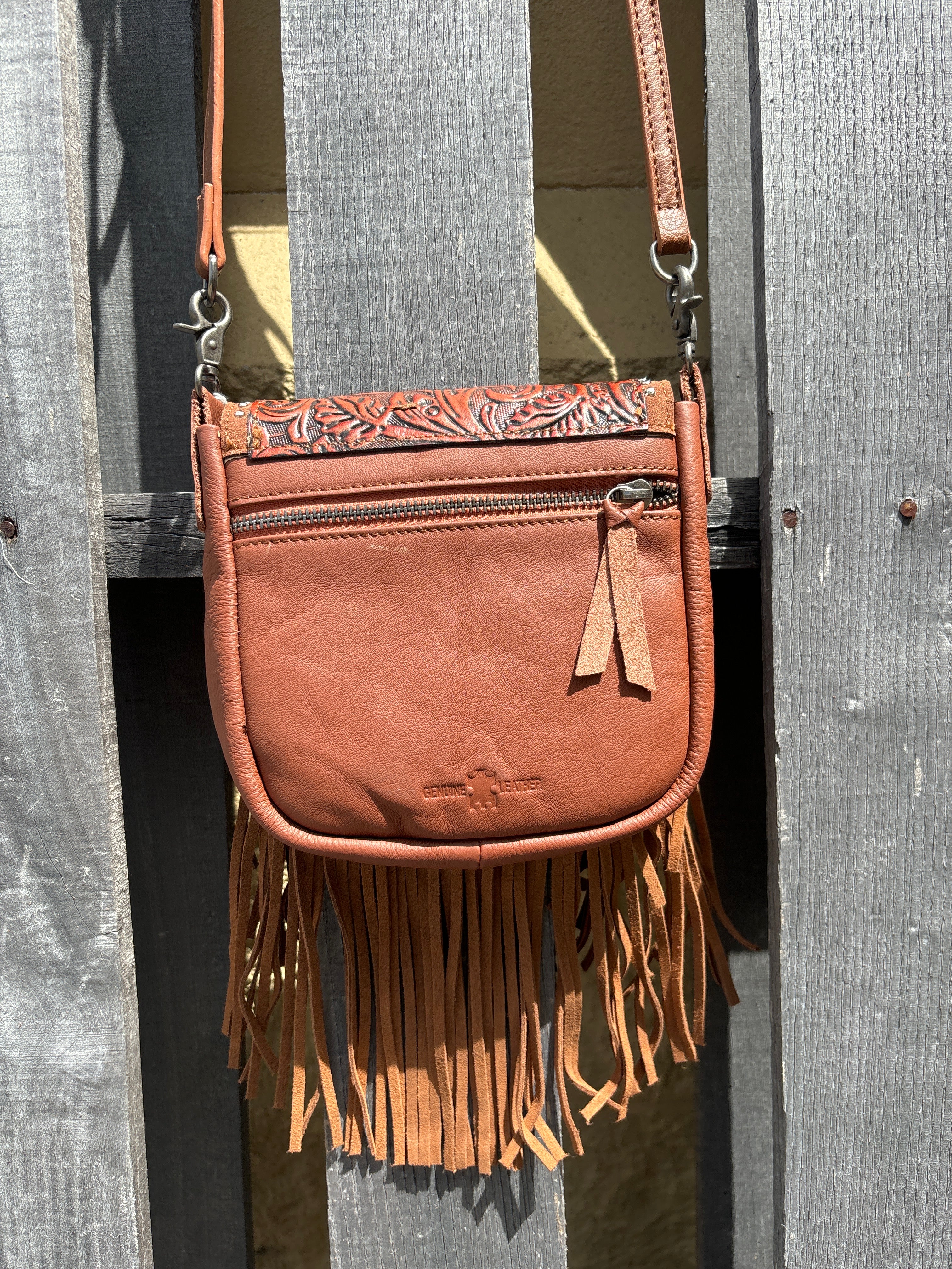 Brown leather crossbody bag with a fringe sides and a tooled design on the flap. Rear View