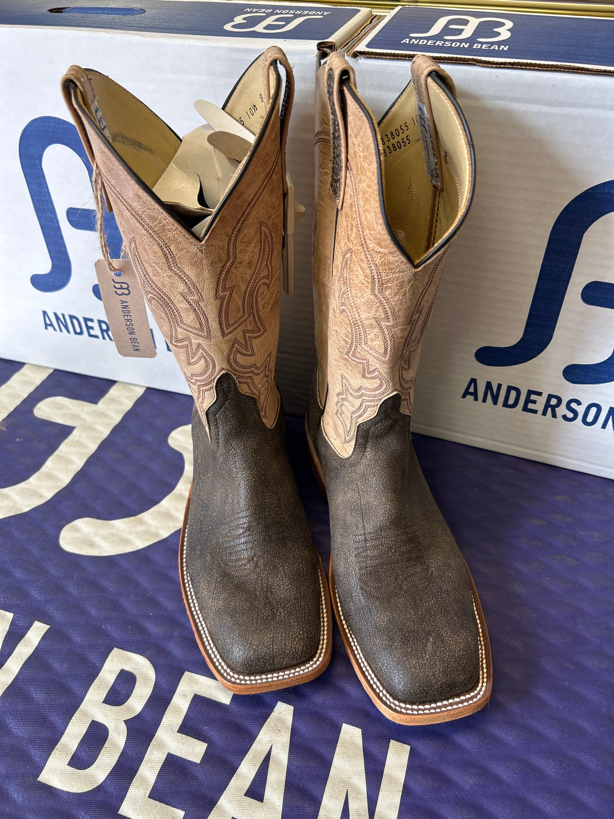 Pair of cowboy boots on a blue and white box with 'Anderson Bean' branding.