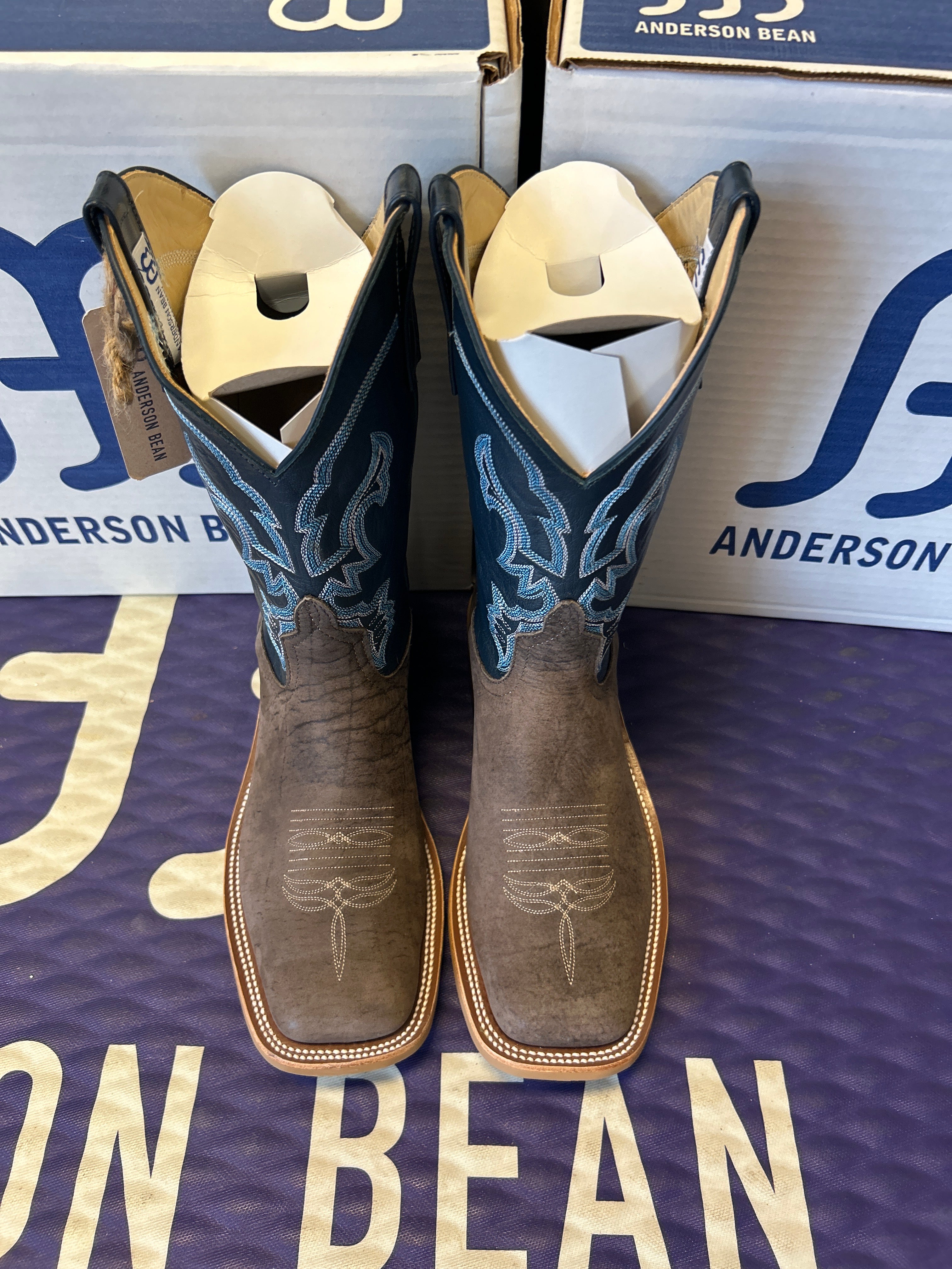 Pair of cowboy boots on a blue Anderson Bean branded surface