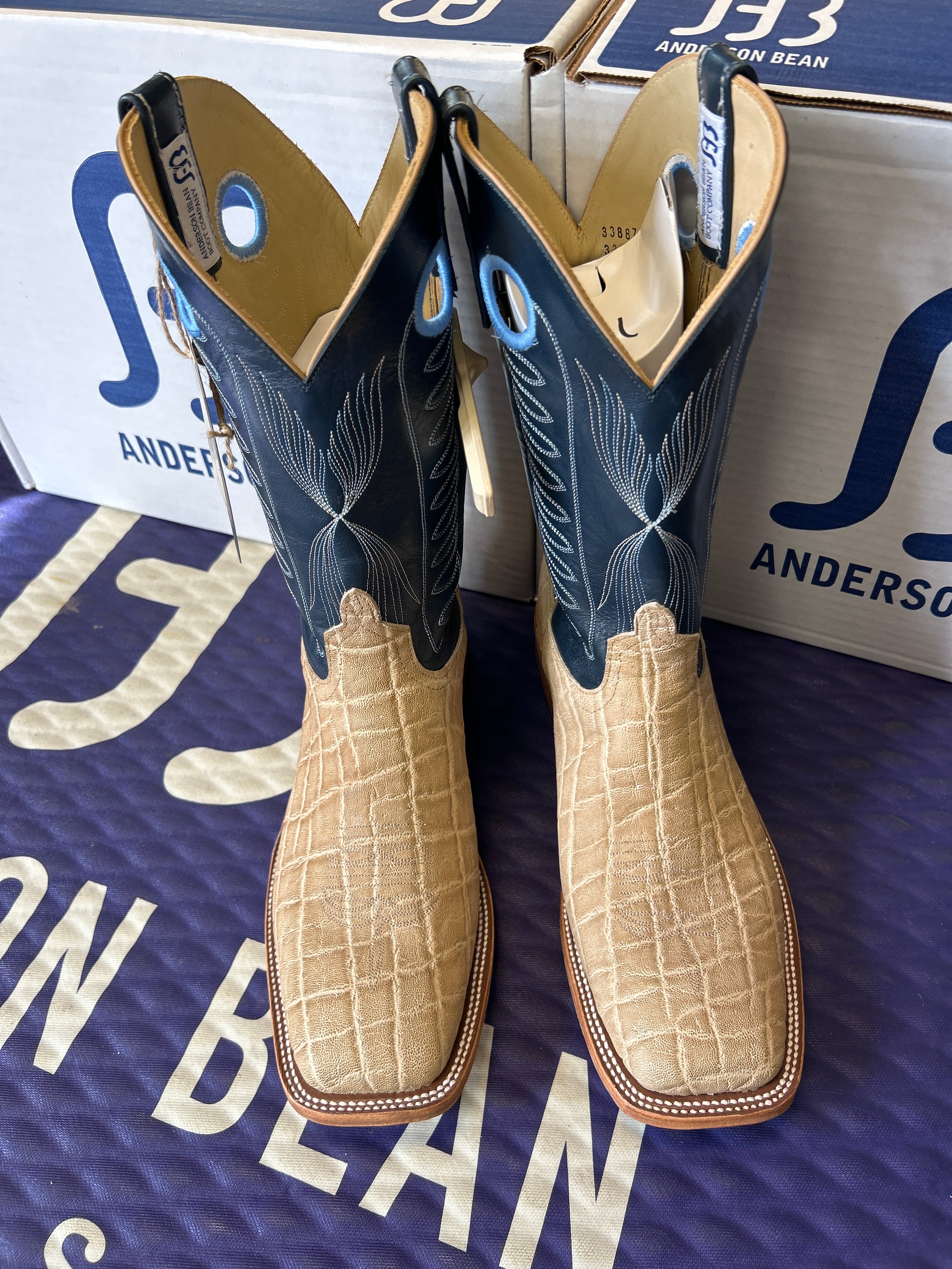 Pair of cowboy boots with a box labeled 'J. M. Weston' on a blue background.