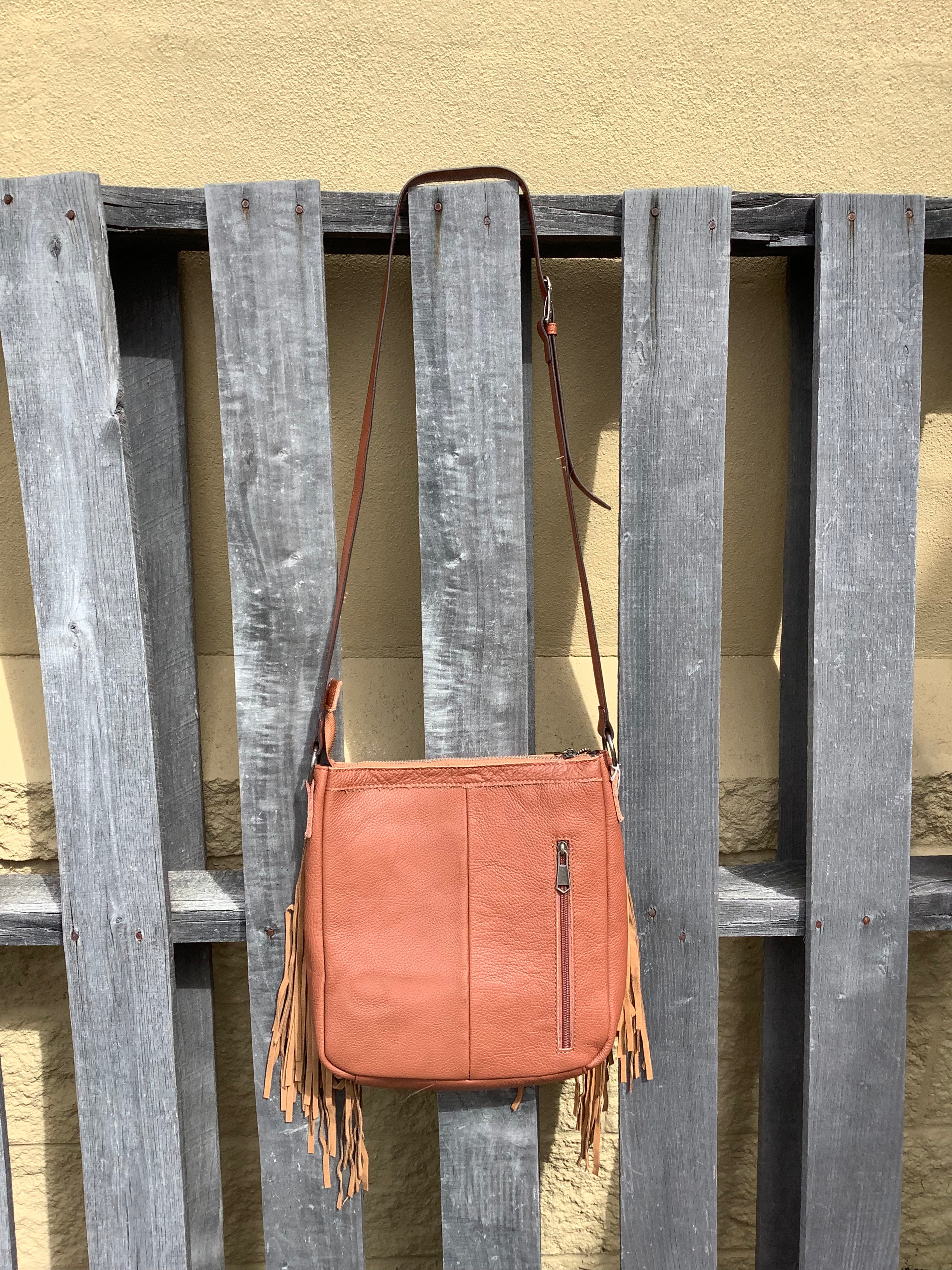 This Brown leather and cowhide shoulder bag has side fringe and a tooled leather design on the top. It has a rear concealed carry pocket. Rear view showing concealed carry pocket. 