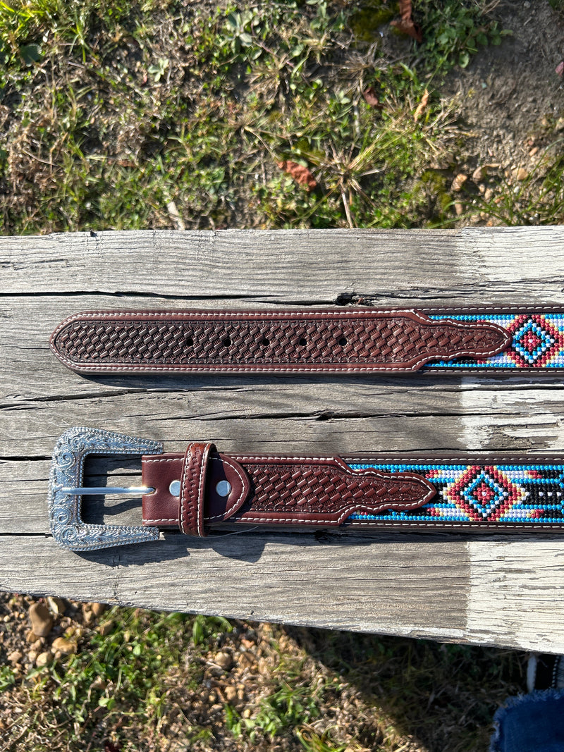 This Red and Blue embroidered belt has a basketweave leather overlay on each end with a matching keep. The Silver buckle has a intricate design featuring a Longhorn. Close up view of both ends showing the basketweave leather overlay. 