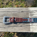 This Red and Blue embroidered belt has a basketweave leather overlay on each end with a matching keep. The Silver buckle has a intricate design featuring a Longhorn. Close up view of buckle and keep. 
