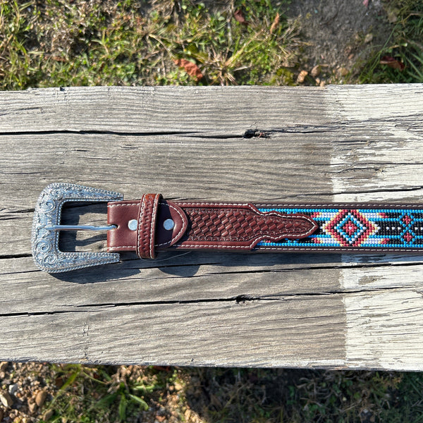 This Red and Blue embroidered belt has a basketweave leather overlay on each end with a matching keep. The Silver buckle has a intricate design featuring a Longhorn. Close up view of buckle and keep. 