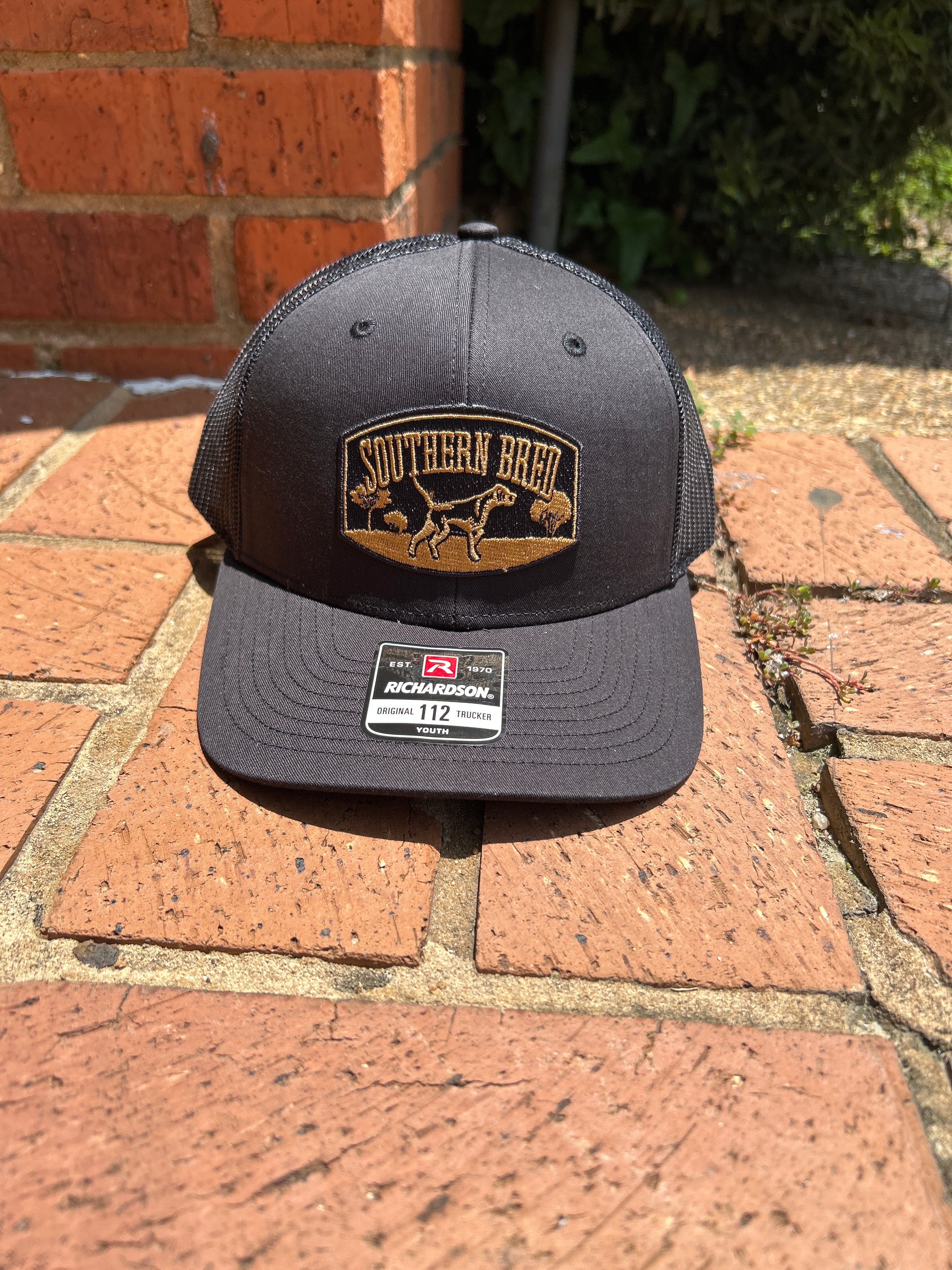 Black cap with a logo on a brick surface