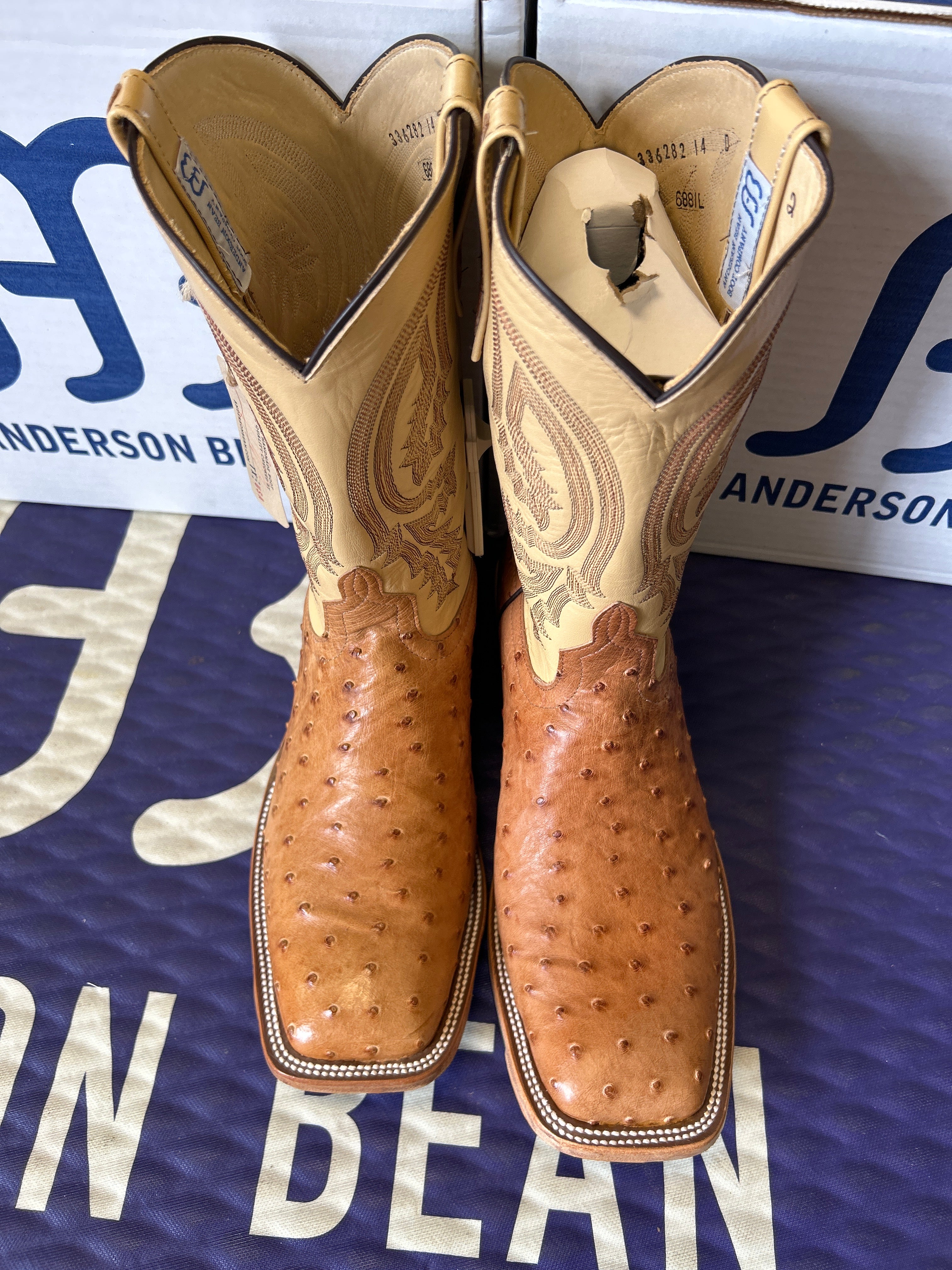 Pair of brown leather gloves with a brand logo in the background