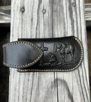 A black leather knife sheath with a keep, features a embossed design of a Praying Cowboy. Front View