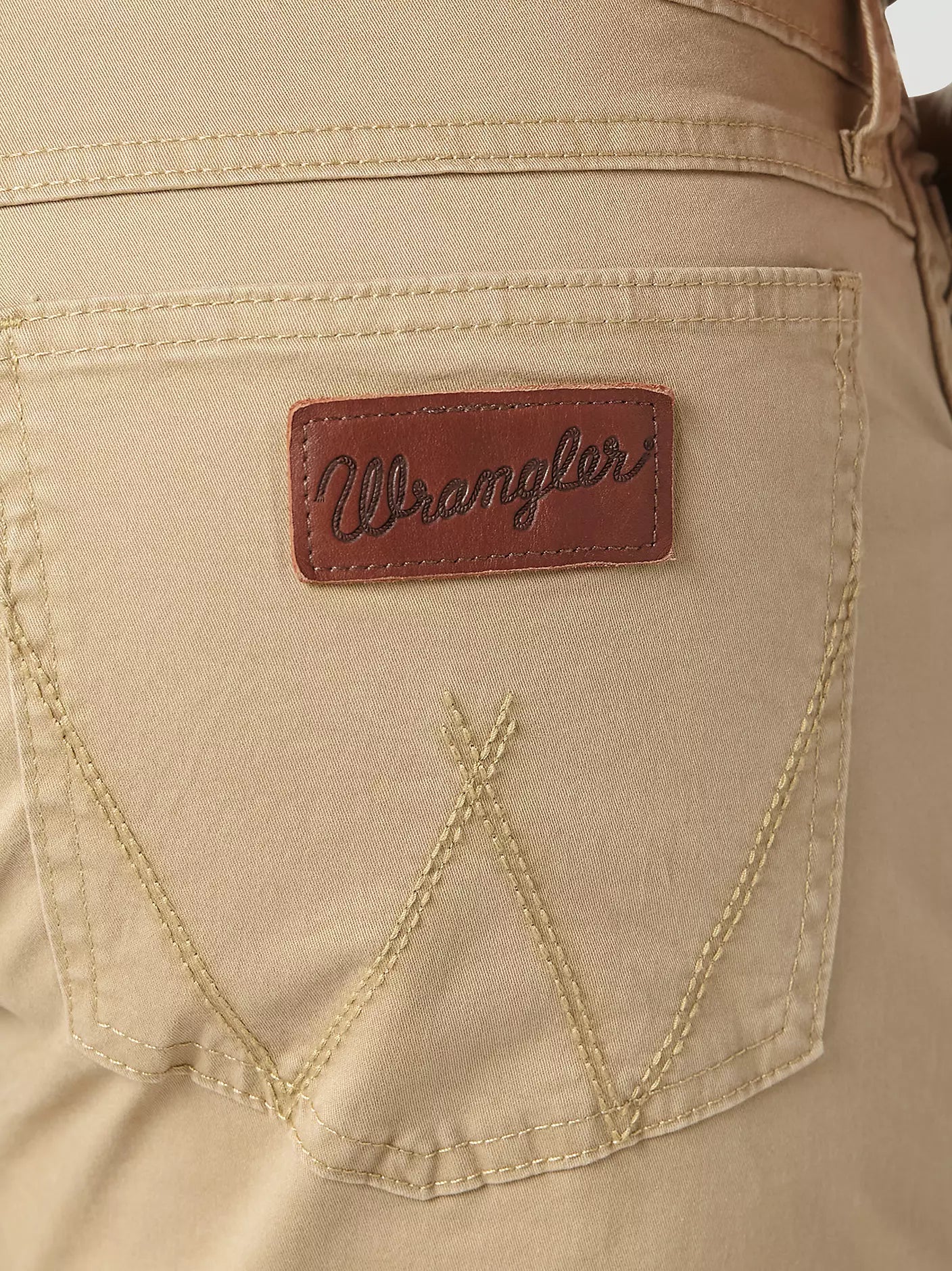 Closeup of back right back pocket of a man wearing Wrangler Retro fawn  slim fit straight leg jeans. Pocket has Wrangle "W" and neolite brown logo patch.