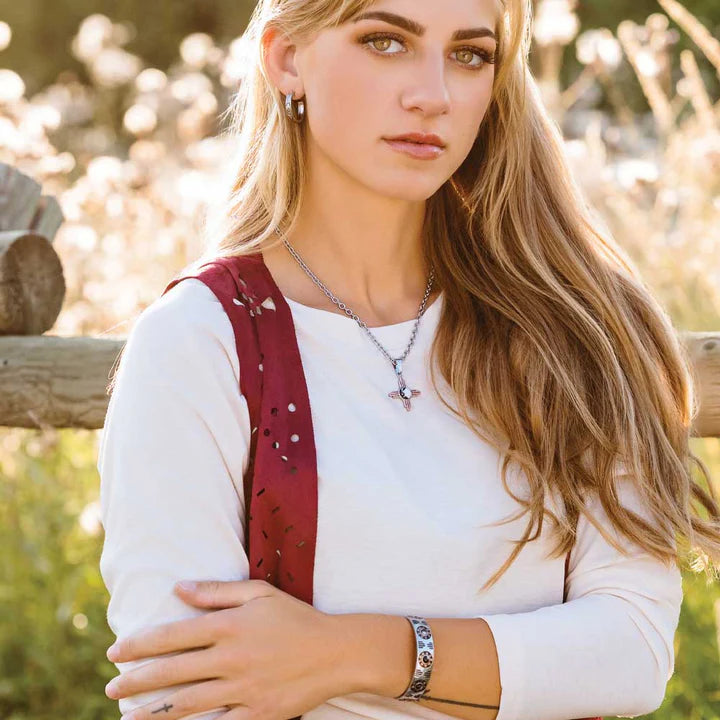 This Silver Cuff bracelet featuring a rose gold tone and deep black paint etched into a Southwestern pattern that continues around to the back of the bracelet. It also features three round howlite stones at the top of the cuff. Shown on model