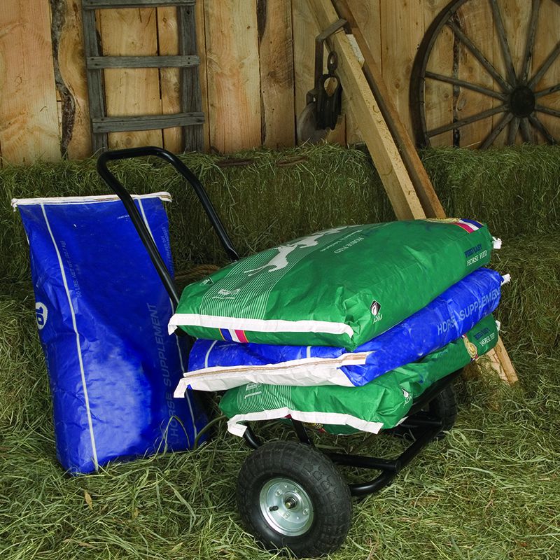 Black Little Giant muck cart shown loaded with sacks of feed.
