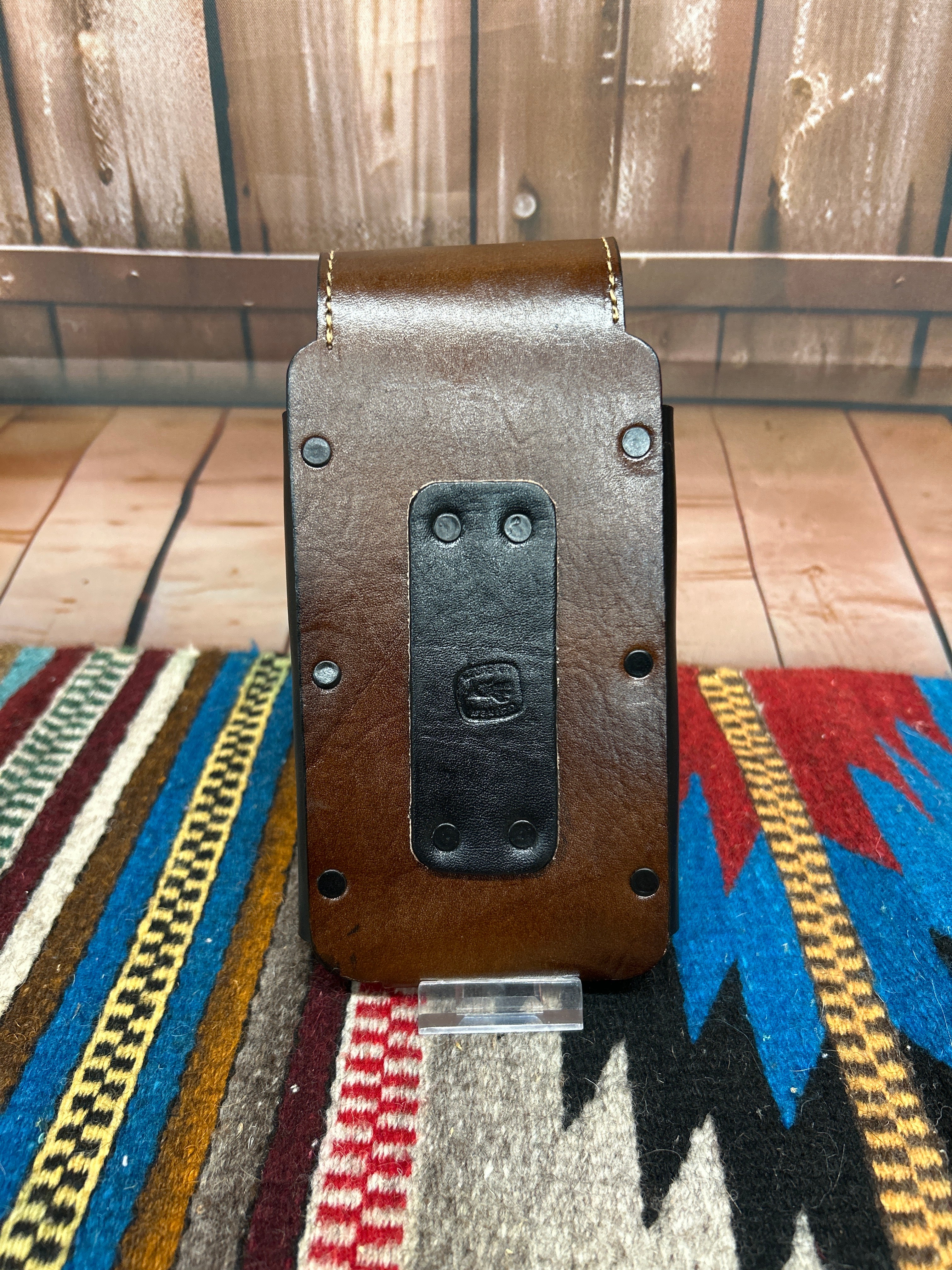 This leather phone case has a Praying Cowboy design on the front. It has a snap closure and a leather belt loop for attachment. This case measures 7 1/4 inches tall, and 3 5/8 inches wide empty. Rear View 