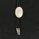 A bolo tie with a black braided leatherette cord, silver colored tips, and an oval silver colored western engraved concho with gold colored rope edge.
