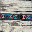 This Red and Blue embroidered belt has a basketweave leather overlay on each end with a matching keep. The Silver buckle has a intricate design featuring a Longhorn. Close up view of pattern.