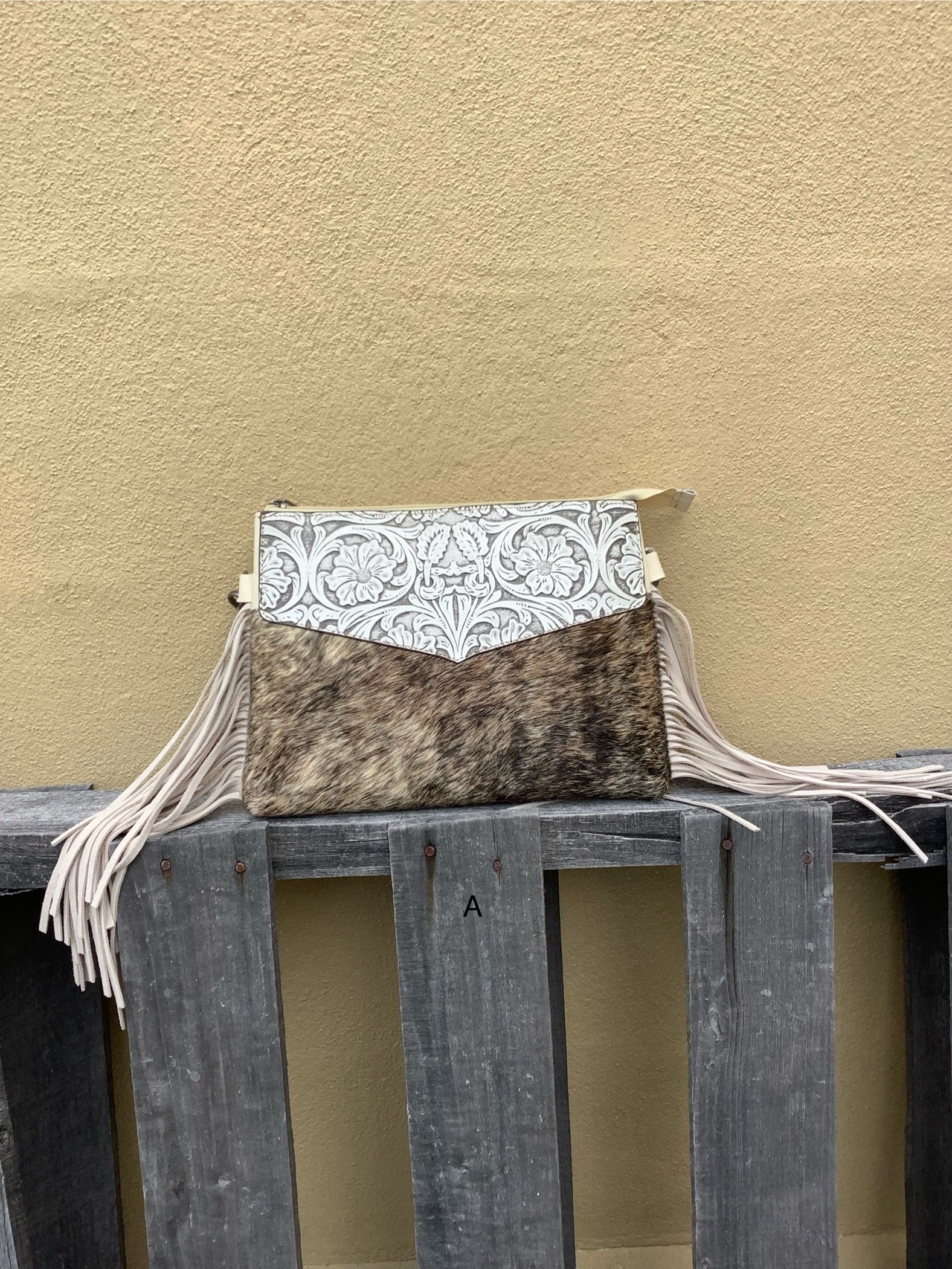 Beige tooled leather and cowhide purse with fringe details and a zippered closure. Front View A