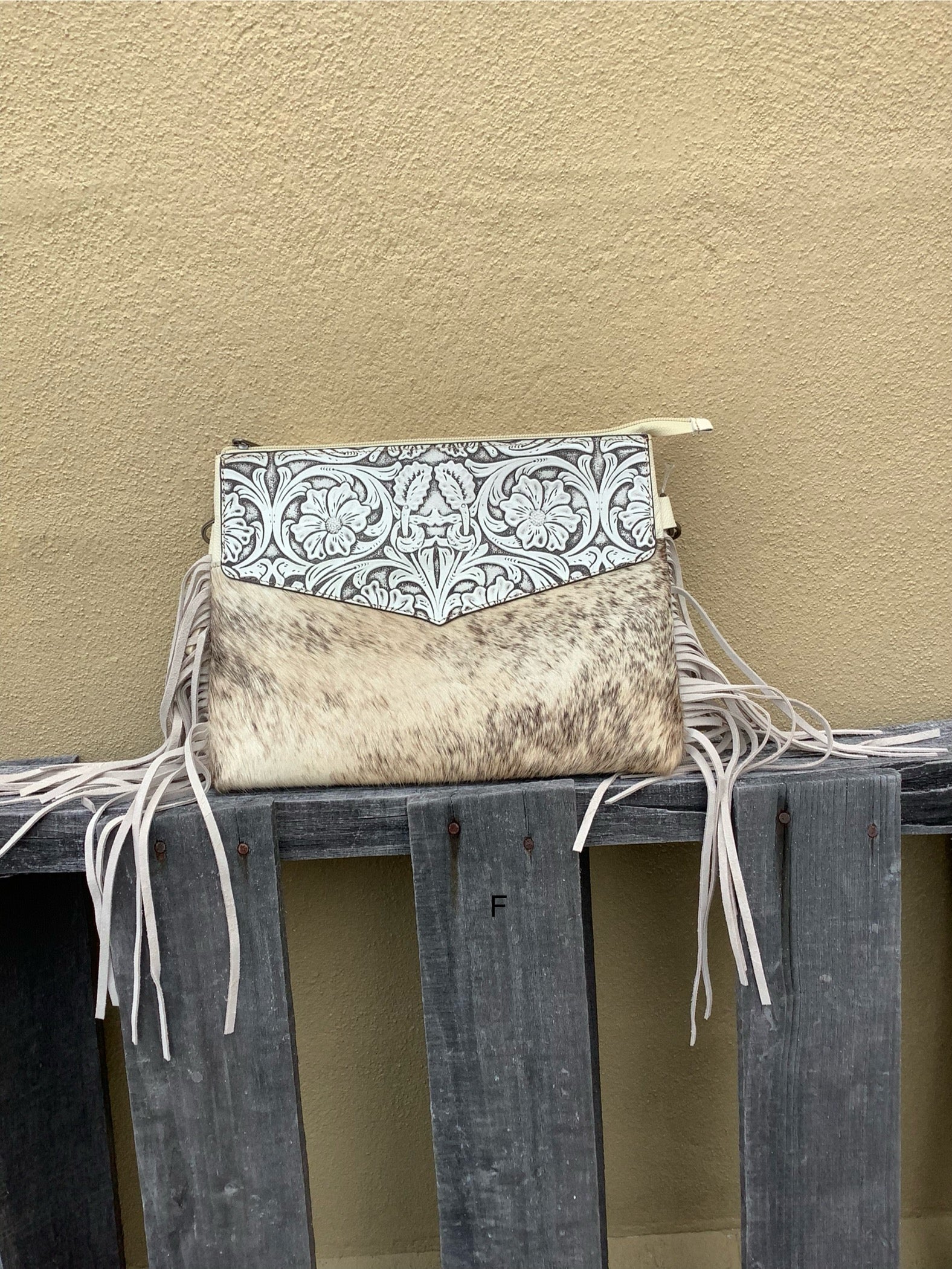Beige tooled leather and cowhide purse with fringe details and a zippered closure. Front View F