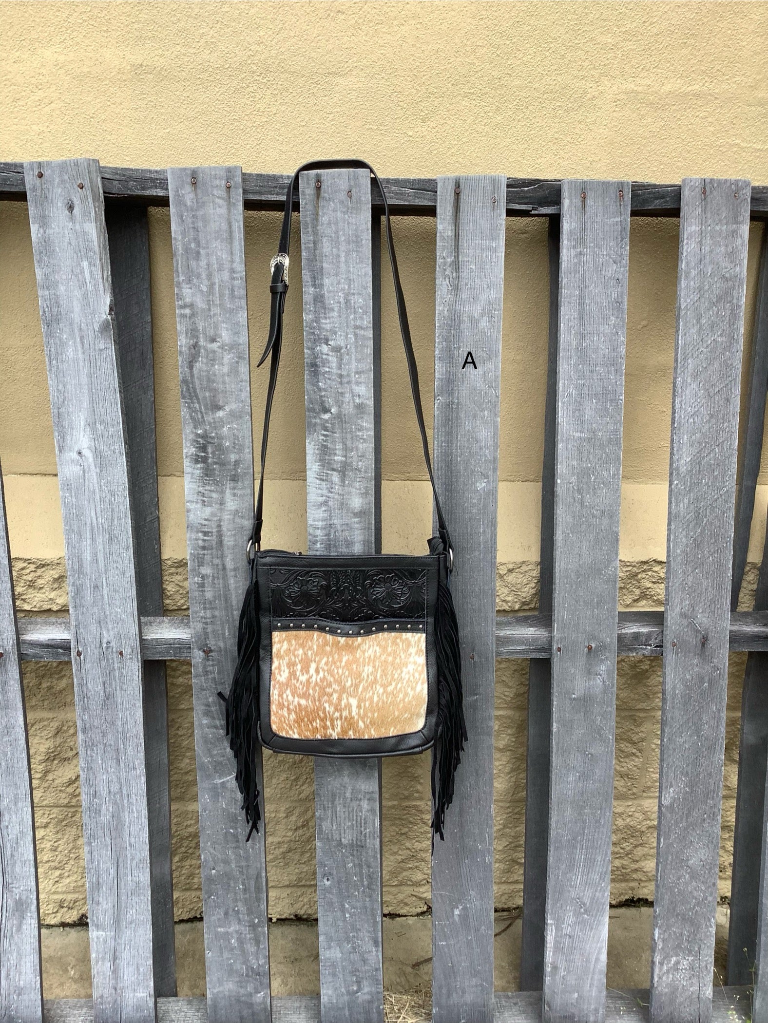 This Black leather and cowhide bag has side fringe and a tooled leather design. It has a rear concealed carry pocket. Front View A