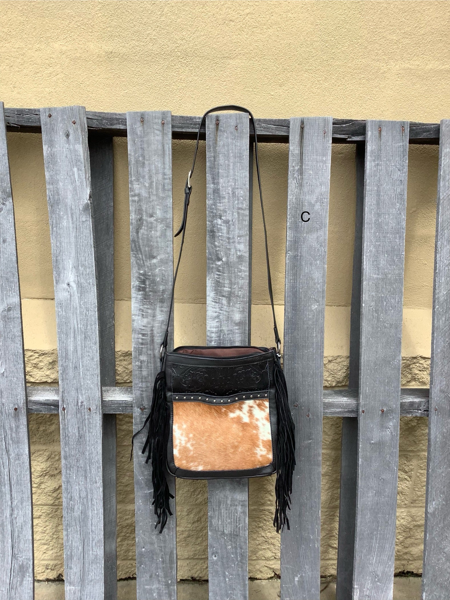 This Black leather and cowhide bag has side fringe and a tooled leather design. It has a rear concealed carry pocket. Front View C