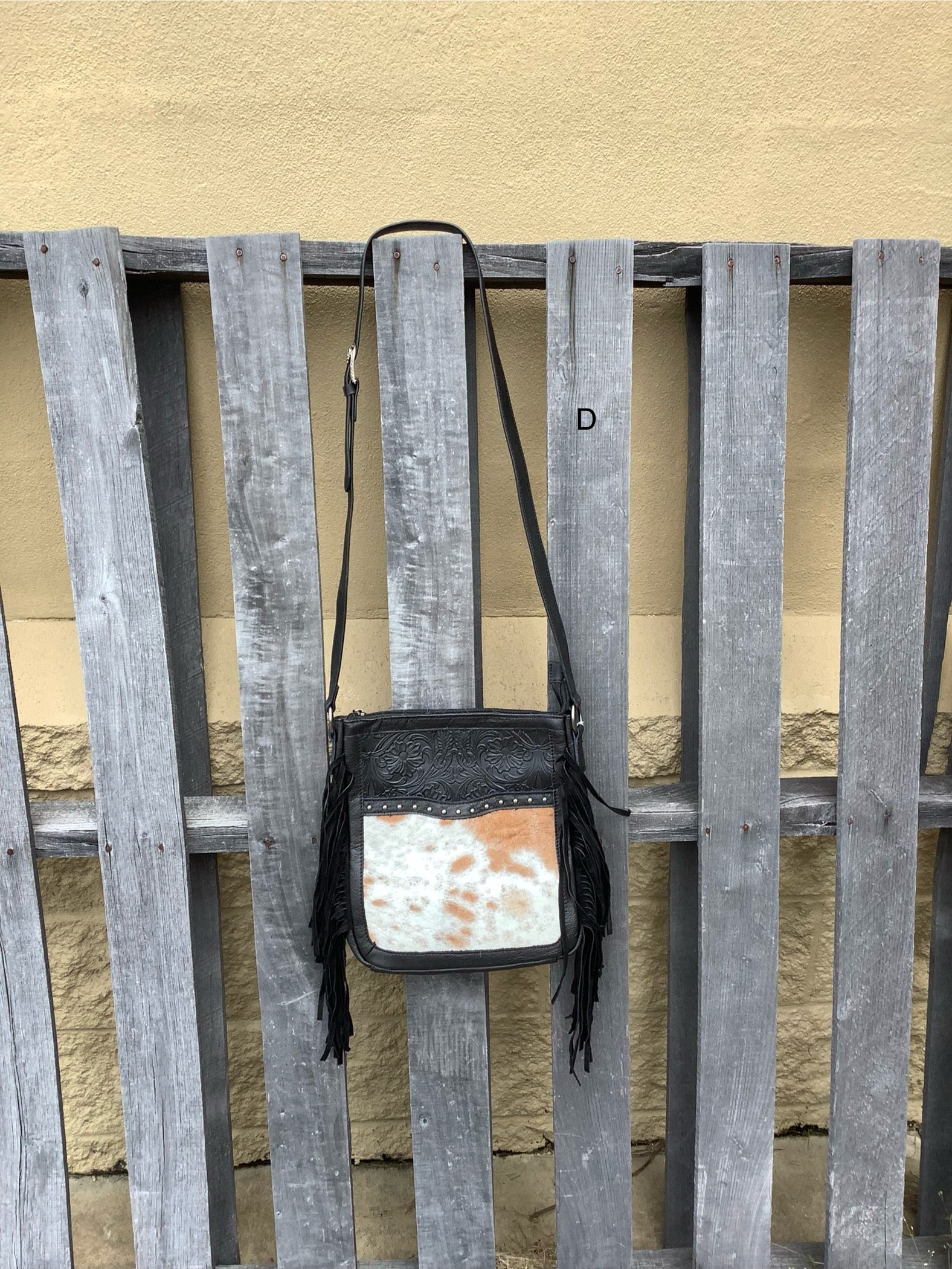 This Black leather and cowhide bag has side fringe and a tooled leather design. It has a rear concealed carry pocket. Front View D