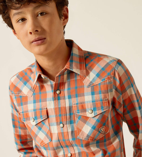 Boy's Ariat long sleeve Retro fit snap shirt in Arabesque, a orange and blue plaid. Front view showing both chest pockets with snap closure and a Ariat shield logo on left chest pocket. 