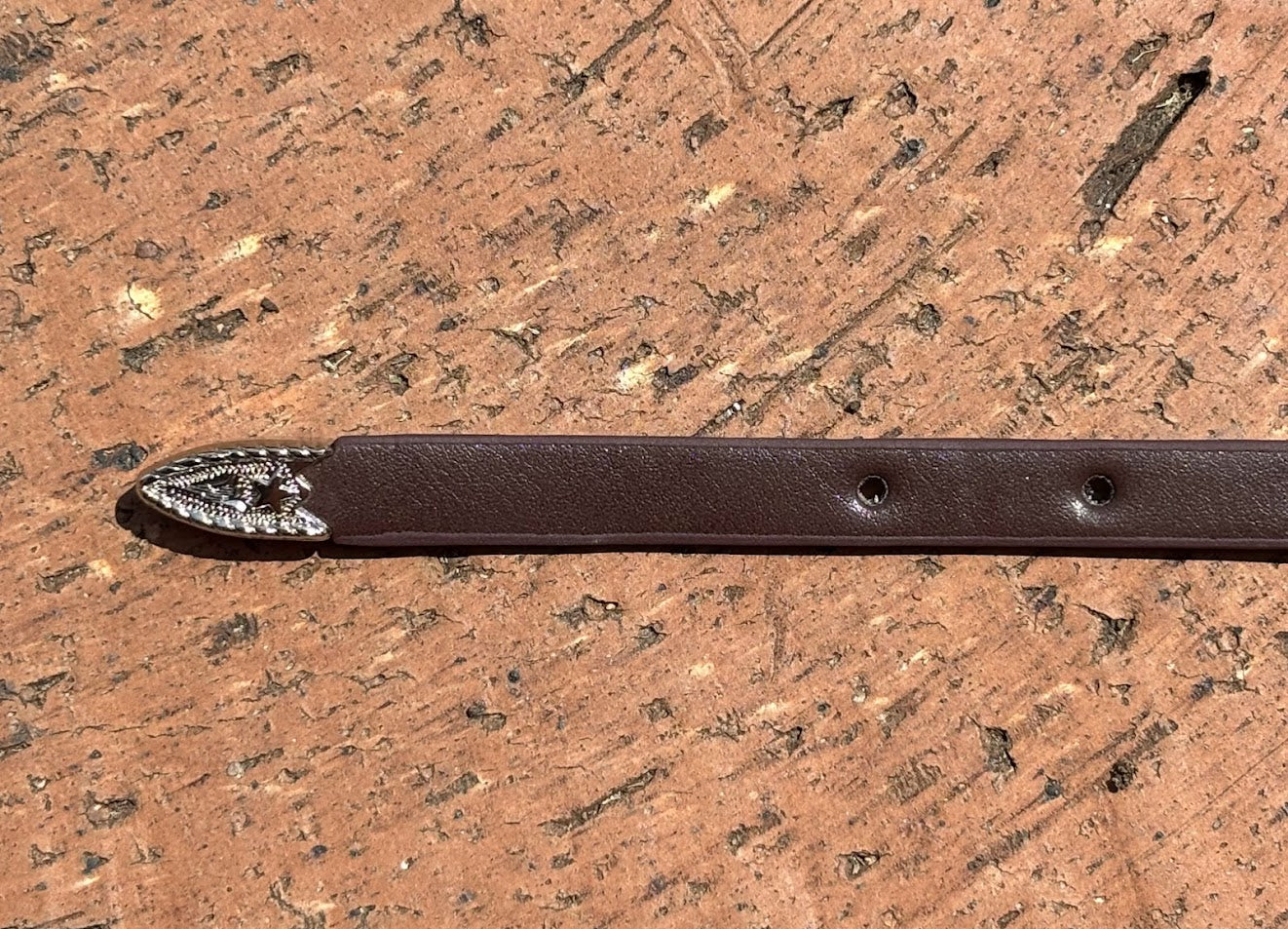 Coffee Brown leather hat band with silver tip on a wooden surface