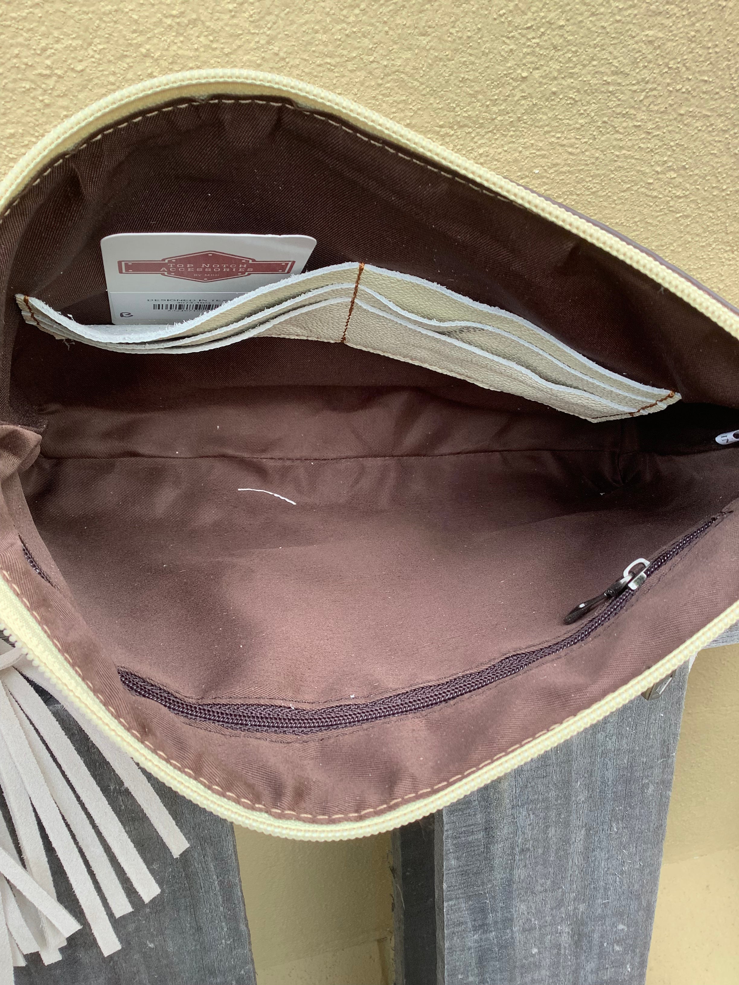 Beige tooled leather and cowhide purse with fringe details and a zippered closure. Inside view showing card slots and zippered pocket. 
