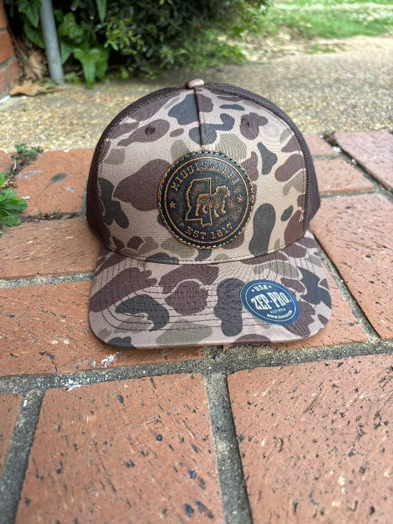Leather circle patch with Mississippi Established 1817 and a bulldog on a old school brown camo Richardson 112PFP cap. Cap features a brown mesh back and is adjustable. Front View