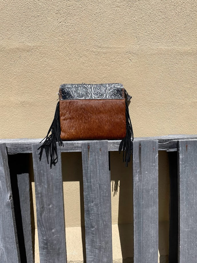 Black embossed leather and cowhide crossbody bag with side fringe. This bag features a zippered closed top and a removable, adjustable strap. Front View B