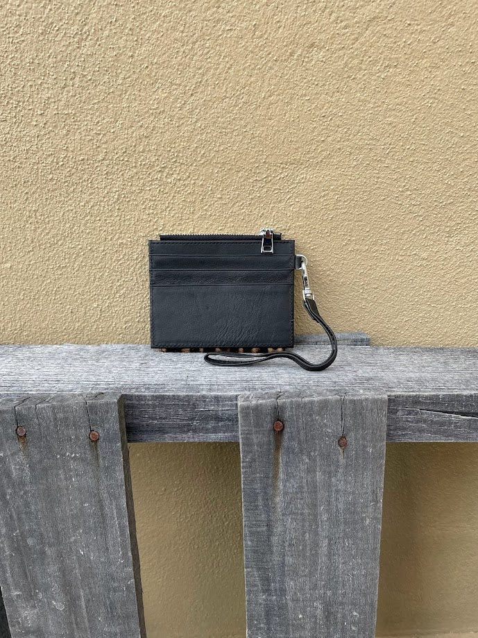 A leopard cowhide keychain wristlet wallet. Rear view showing solid black leather back with card slots. 