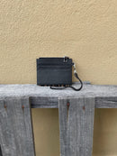 A leopard cowhide keychain wristlet wallet. Rear view showing solid black leather back with card slots. 