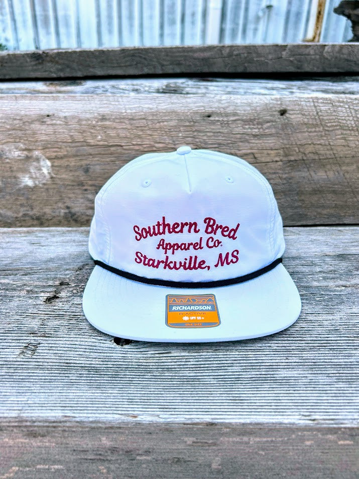 Southern Bred Apparel Co Starkville, MS white cap with black rope. 
Front View