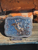 Silver and Gold western style belt buckle with a Bull Rider design and a Pink rhinestone border. 