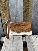 Cowhide wristlet purse with a solid Brown leather back and a zippered closure. It features a wristlet strap and and a adjustable removable shoulder strap. Front View E