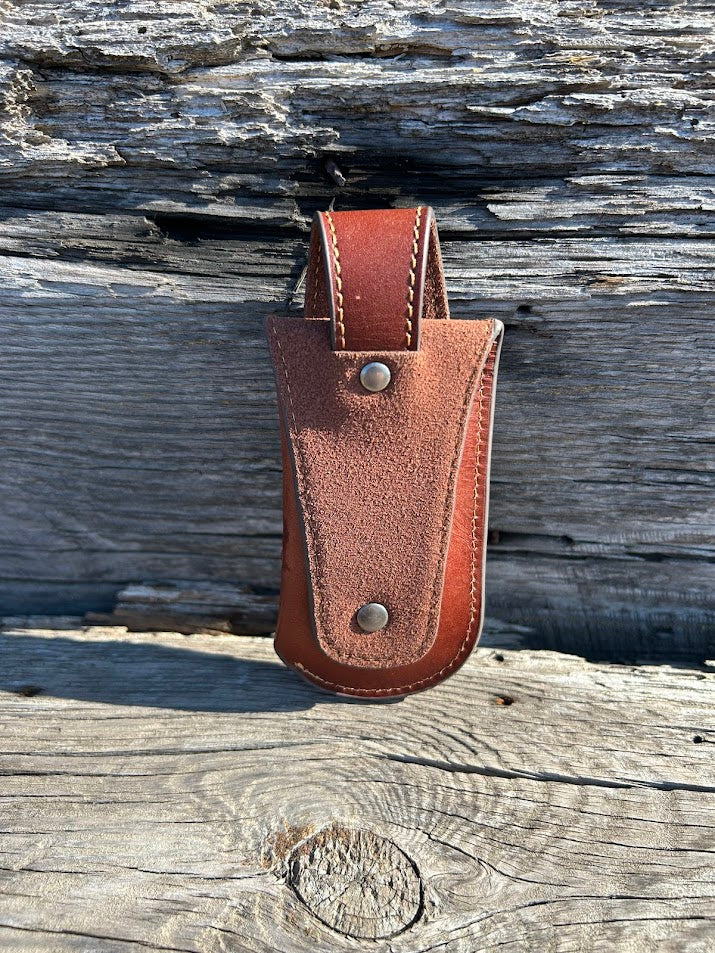 Brown leather knife sheath with a embossed Bull Rider design. It has a keep closure and a belt loop attachment. Rear View