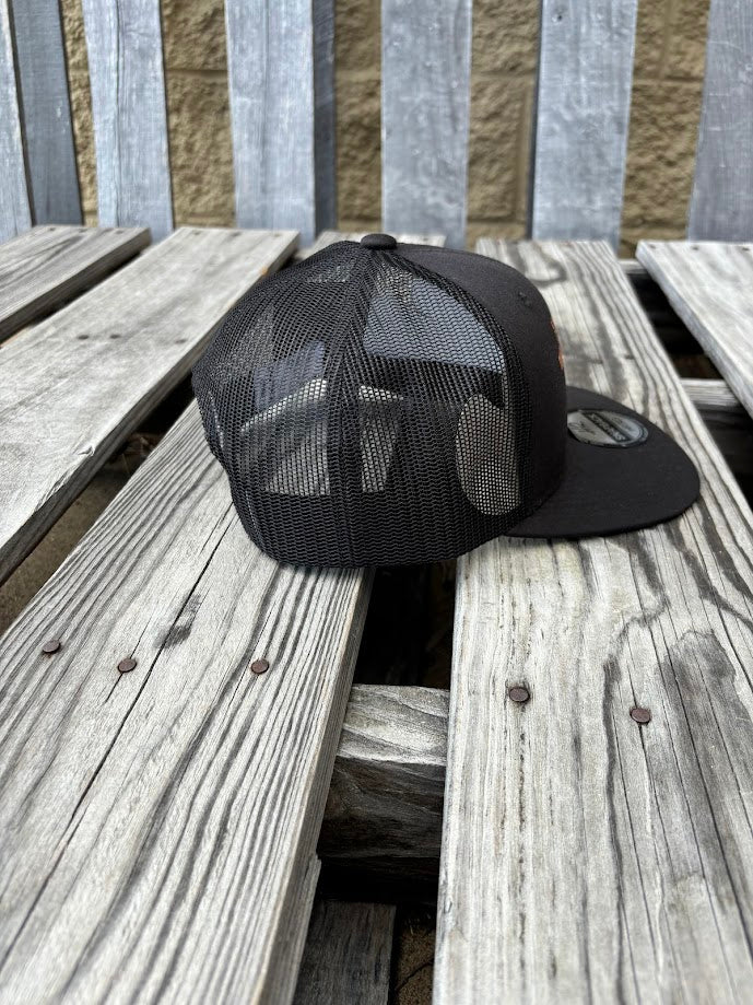 A black snapback cap with a embroidered praying cowboy design. Side View