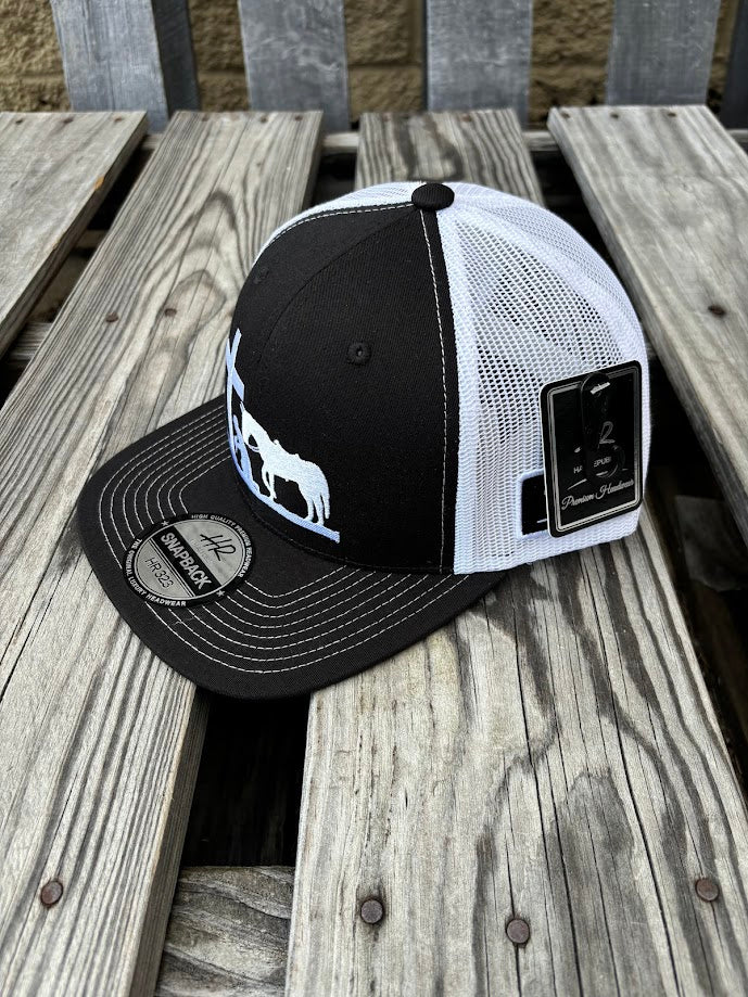 A Black and White snapback cap with a embroidered praying cowboy design on the front. Side View