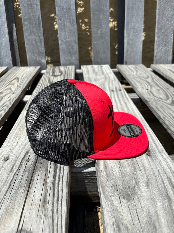 A Red and Black snapback cap with a embroidered praying cowboy design on the front. 