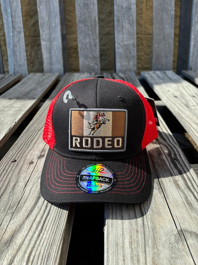 A Black trucker cap with a Red mesh back featuring a 'RODEO' Bull Rider patch on the front. Front View