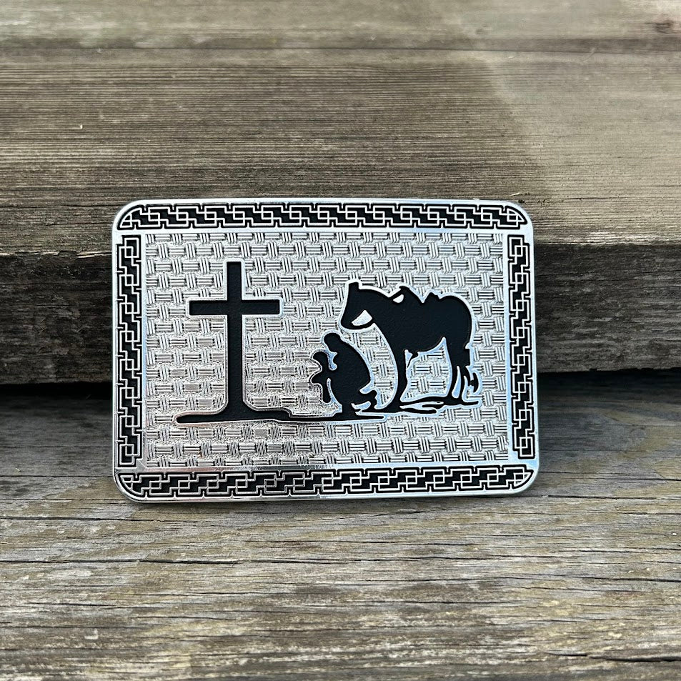 This silver and black buckle features a Praying Cowboy design on a Silver rectangle featuring Black accents and a intricate border. Front View 