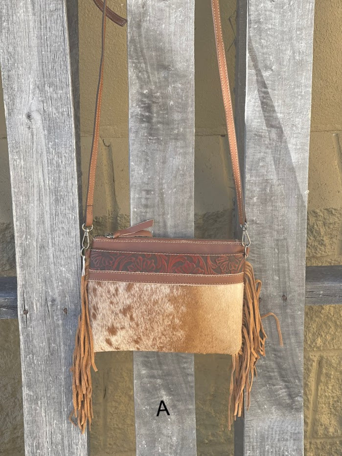 Brown leather and cowhide crossbody bag with side fringe. Front View A showing hanging from shoulder strap. 