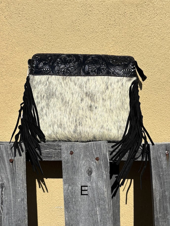 Black embossed leather and cowhide crossbody bag with side fringe. This bag features a zippered closed top and a removable, adjustable strap.  Front View E