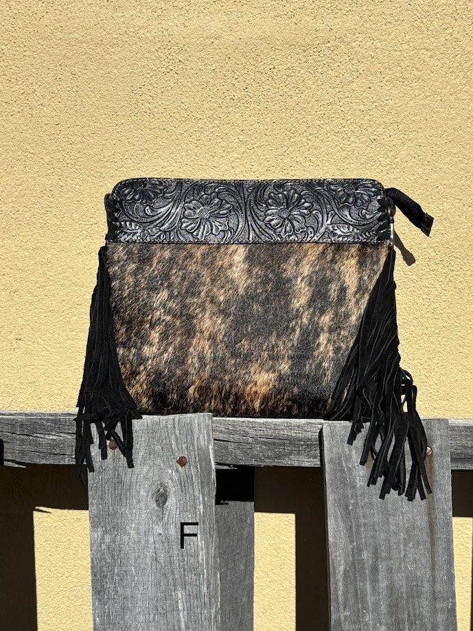 Black embossed leather and cowhide crossbody bag with side fringe. This bag features a zippered closed top and a removable, adjustable strap. Front View F
