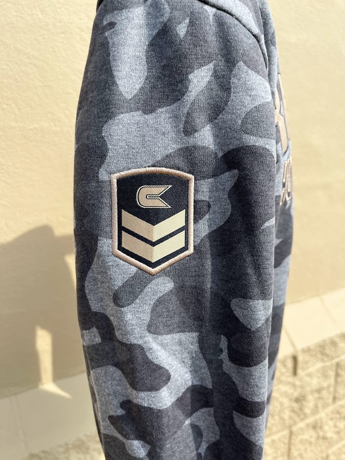 Colosseum Athletics Louisiana State University hoodie in Pavement/Heather Camo. This hoodie support the Operation Hat Trick foundation and has patches on the sleeves and near the front pouch pocket. Full front view shown on mannequin. Sleeve detailing showing patch. 